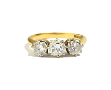 A gold and platinum, diamond set three stone ring, claw set with a row of circular cut diamonds, detailed 18 CT & Pt, ring si