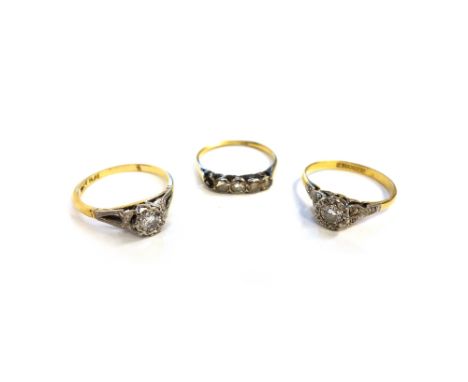 A gold and platinum, diamond set single stone ring, mounted with a circular cut diamond, between rose diamond set three stone