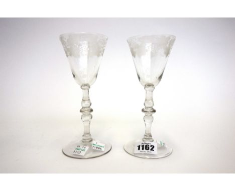 A pair of English engraved wine glasses, circa 1750, each with a rounded funnel bowl and 'Newcastle' light baluster stem, on 