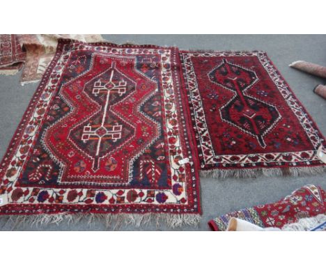 A Shiraz rug, South Persian, the madder field with a dual medallion and shaped black surround, with flowerhead motifs, an ivo