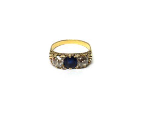 A gold, diamond and sapphire set three stone ring, mounted with the cushion shaped sapphire at the centre, (the sapphire very