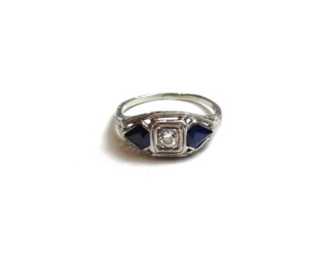 A white gold, diamond and sapphire set three stone ring, mounted with the circular cut diamond at the centre between two kite