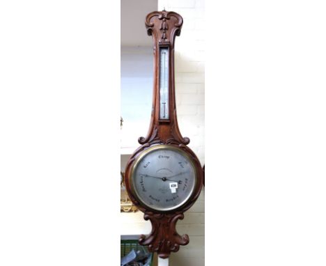 A Victorian oak cased wheel barometer, with all over foliate carving and applied thermometer, over a ten inch silvered dial d
