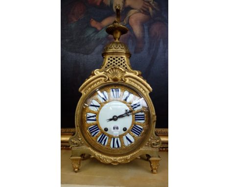 A Louis XIV style ormolu mantel clock, early 20th century, with a Grecian oil lamp finial over a 10 inch white enamel and orm