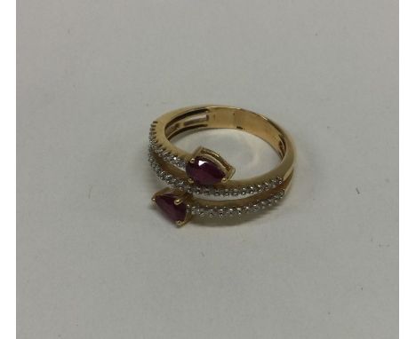 An unusual ruby and diamond crossover ring in 18 carat gold. Est. £400 - £500.