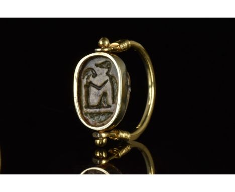 Ca. 1570-1070 BC. A finely modelled swivel ring featuring a gold bezel incorporating a glazed composition scarab inscribed to