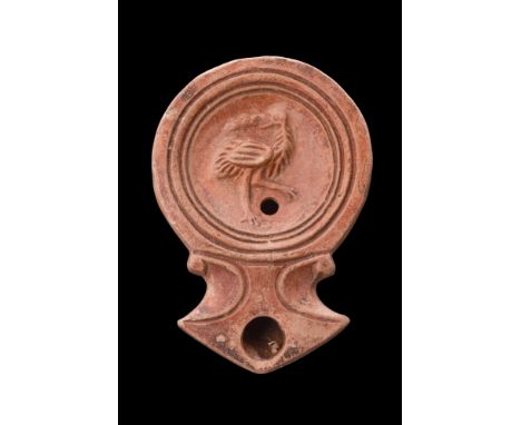 Ca. 1-100 AD. A mould-made terracotta oil lamp with concave discus bearing a relief image of a standing heron facing left. Th