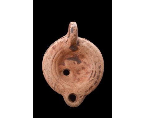 Ca. 100-200 AD. A finely crafted terracotta oil lamp with a small spout for the wick, which is fed with oil through a filling