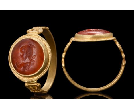 Ca. 100-200 AD. A stunning gold finger ring of a flat-section hoop with nicely decorated shoulders and a bezel set with a car