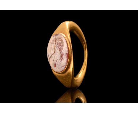 Ca. 200-300 AD. A large and impressive 23K yellow gold ring with a remarkable carved intaglio of cream and red agate reveals 