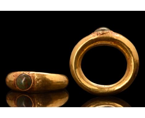 Ca. 100-300 AD. A gold finger ring of carinated, round-section band tapering to the back. Bezel set with an emerald stone. Th