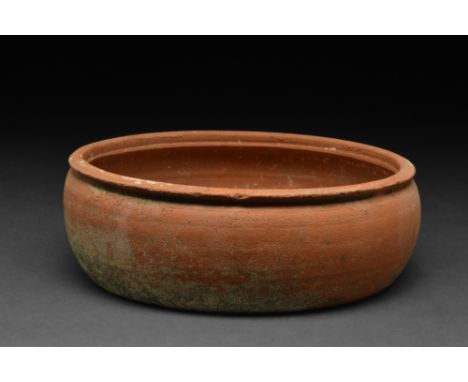 Ca. 300-400 AD. A terra sigillata dish comprising a round-bottomed bowl with high sides that end in a thick everted rim. Terr