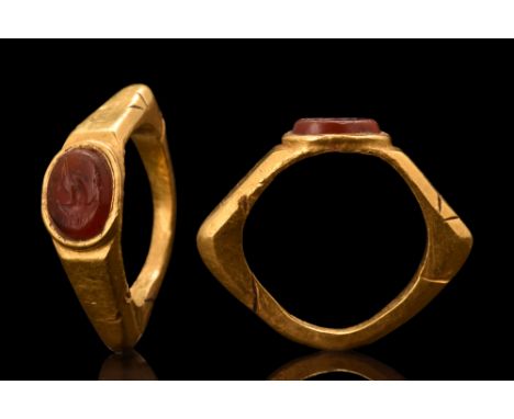 Ca. 100-300 AD. A gold finger ring with expanding hoop, angled and facetted shoulders. Bezel is set with an oval carnelian in