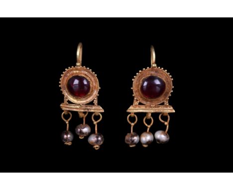 Ca. 100-300 AD. A stunning matched pair of gold earrings, each comprising a gold hook attached to a round setting with a larg