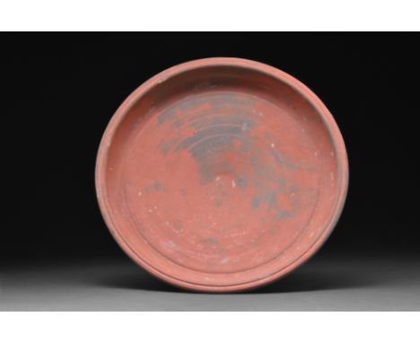 Ca. 1-300 AD. A large terracotta shallow plate or dish with its walls gently tapering to a low ring base. 'Terra sigillata' i