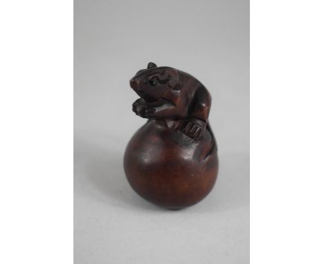 A Carved Wooden Netsuke in the Form of a Rat on a Ball 