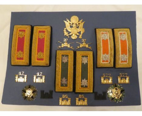 A display of United States Army insignia including brass cap badge, Major Ordnance shoulder boards, Lt.Col. Signals shoulder 