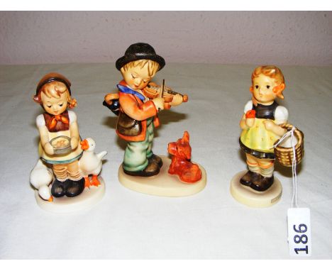 Three Goebel figurines including one titled "Be Patient", one figurine of a boy with a violin and a dog and a girl with a bas