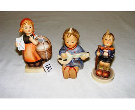 Three Goebel figurines including a boy seated with a mandolin, a boy figurine entitled "Little Hiker" and a lady with a baske