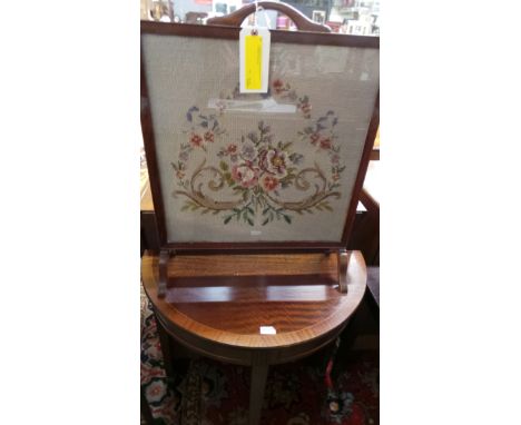 A mahogany demi lune console table and a needlework firescreen