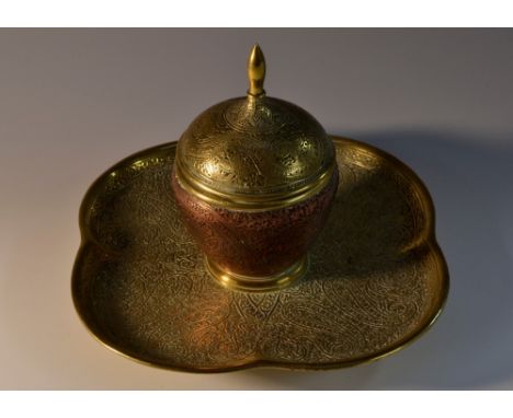 A 19th century brass and copper desk inkwell, in the Indian taste, chased with stylised leaves on scrolling stems, hinged cov