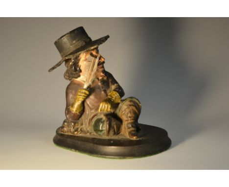 A 19th century papier mache inkwell, as a 17th century gentleman, seated, with quill in hand, oval ebonised base, 11cm high  