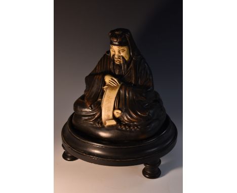 An Art Deco composition wireless speaker, as a Chinaman, seated in mediation, holding a scroll, ebonised base, 34cm high, c. 