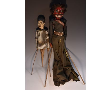 An Indonesian carved and painted  wayang golek puppet, as a red-faced demonic figure, dressed in a long black robe, 74cm long