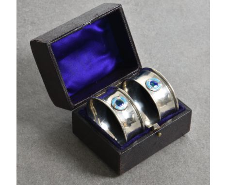 A pair of cased Arts and Crafts silver and enamel napkin rings  Charles Horner, Chester, 1920, of circular form, each having 