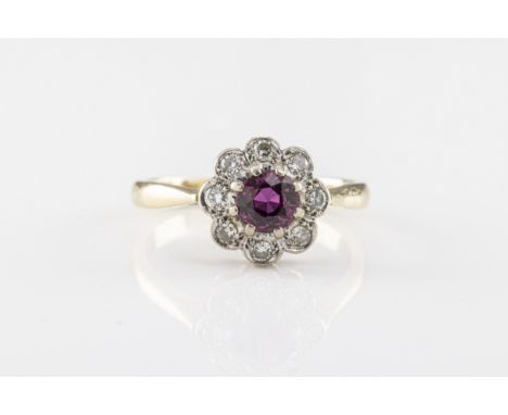 An 18ct yellow gold, ruby and diamond cluster ring  marked '18CT', the central round cut ruby within a floral style border of