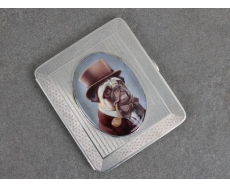 A silver and enamel cigarette case,  the oval enamel cartouche transfer printed depicting a pug wearing a top hat and smoking