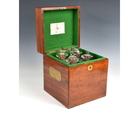 A Georgian 19th century tantalus  comprising a mahogany case containing a silver stand with a loop handle on four scrolling f