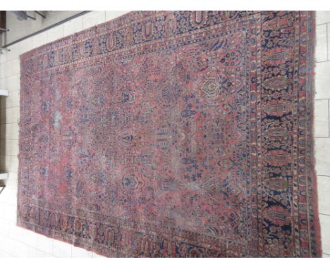 A large antique Sarouk Carpet, multi-bordered with floral motifs on a red ground, 15ft 7in x 10ft 6in