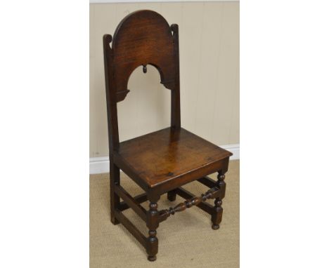 A 17th Century oak Side Chair with plain deep arched splat having acorn finial, solid seat on turned and square front legs un
