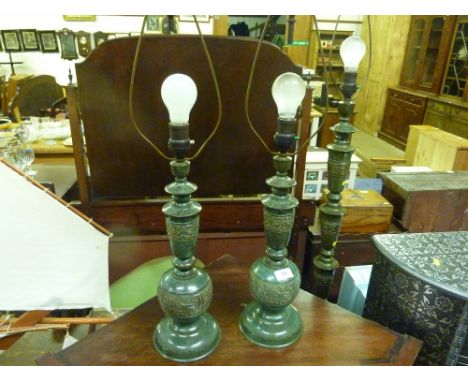 A pair of Eastern metal table lamps together with a similar standard lamp
