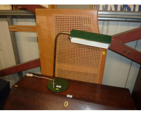 A cane headboard and a brass and metal desk lamp