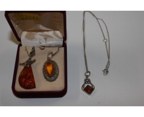 Three vintage silver mounted amber pendants and chains 