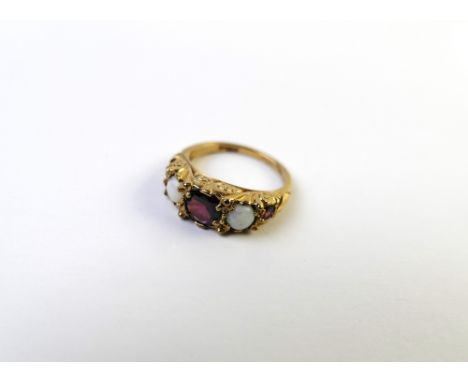 9 ct gold ring decorated with red centre stone flanked by two opal type stones, +/- 3 grams