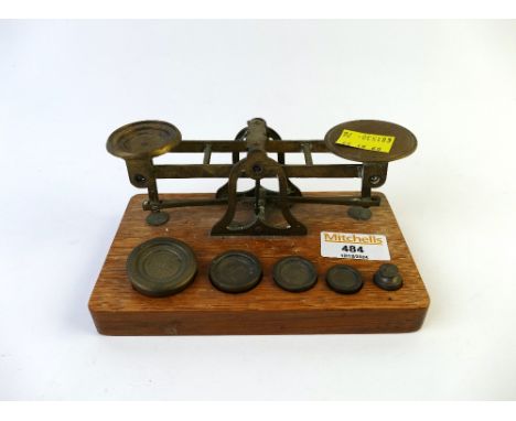 Small set of brass balance scales on wooden plaque with weights