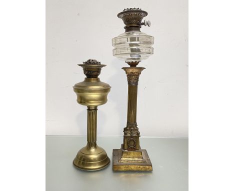 A late 19th century gilt-metal Corinthian columnar oil lamp, with square base and glass reservoir; together with a reeded col