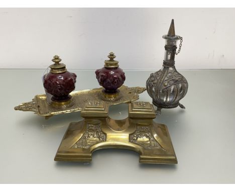 A 19th century brass and glazed pottery double inkstand, the wells in a red glaze, moulded with swagged putti, with hinged br