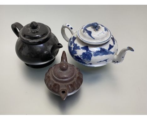 A group of three teapots: the first, Chinese, of compressed spherical form, decorated in blue and white with figures and buil