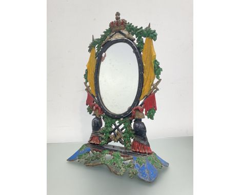 A painted cast-iron toilet mirror, the oval swing plate within a frame cast with military trophies and surmounted by a crown,