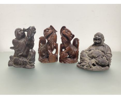 A group of four Chinese wooden carvings: a pair of lion dogs, each with glass eyes, modelled seated; a seated figure drinking