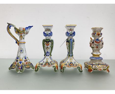 A group of French faience candlesticks comprising: a pair, of flattened baluster form, on square bases with four scroll legs;