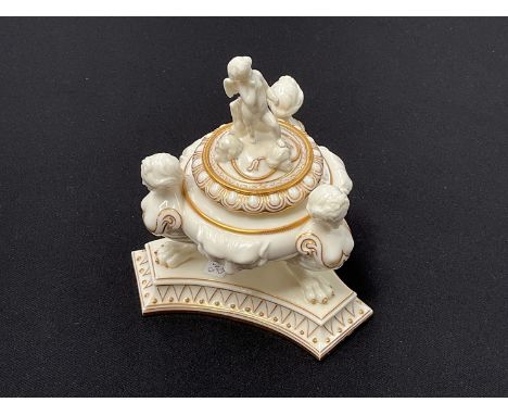 A Worcester cream ground inkwell with mask detail held aloft by three female busts on claw feet over a shaped base, figural k