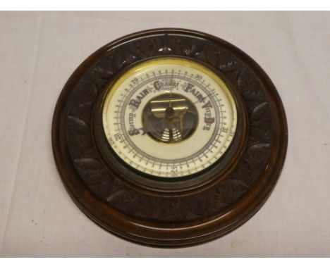 An aneroid barometer with part visible escapement in carved walnut circular case