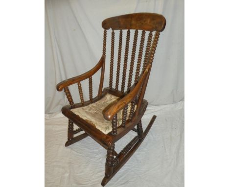 A 19th century elm traditional rocking chair with bobbin turned back and upholstered seat