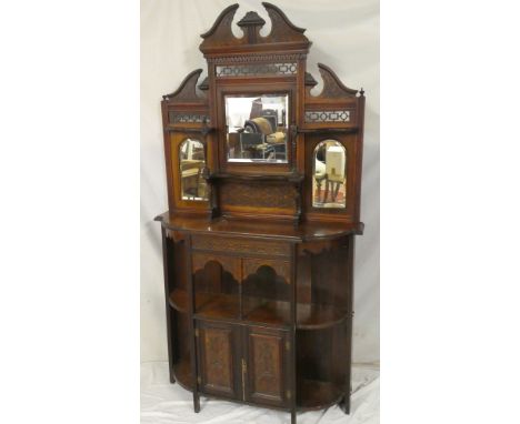 A Victorian carved walnut parlour cabinet with central cupboard enclosed by two panelled doors flanked by open recesses, the 