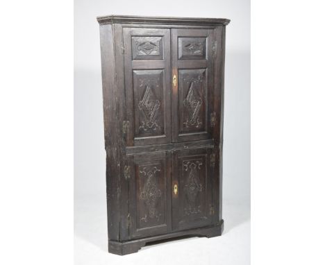 A 17th/18th Century oak freestanding corner cupboard
With a moulded cornice above a pair of panelled doors each centred with 